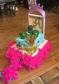 a birthday cake decorated with pink feathers and a mardi gras mask