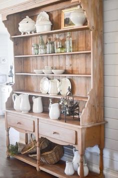 an old wooden hutch with dishes and cups on it's shelves in a kitchen