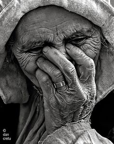 black and white photograph of an old woman covering her face