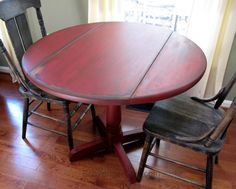 a wooden table with two chairs next to it on a hard wood floor in front of a window