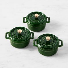 three green casseroles sitting on top of a white counter