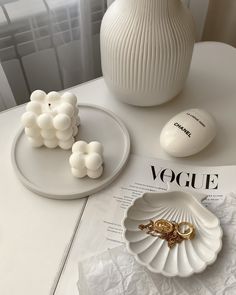 there is a vase, ring dish and other items on the table next to it