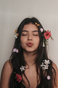 a woman with flowers in her hair blowing out the wind and making a funny face