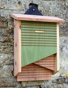 a wooden bird house hanging on the side of a stone wall