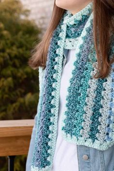 a woman wearing a blue and white crocheted scarf