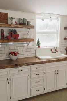 a kitchen with white cabinets and open shelves on the wall above the sink is decorated with christmas decorations