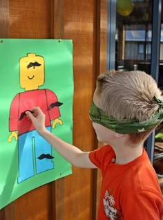 a young boy wearing a bandana standing in front of a door with a paper cut out of legos on it