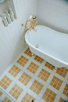 an old fashioned bathtub in a bathroom with yellow and white tiles on the floor