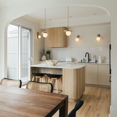 an open kitchen and dining room area with wooden flooring, white walls and cabinets