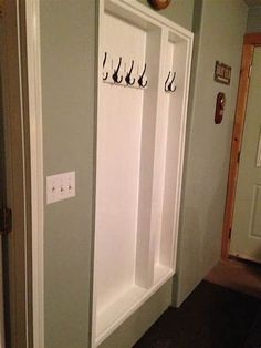 two white benches with coat hooks on them in a hallway next to an open door