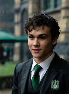 a young man in a suit and tie posing for the camera with rain falling on him