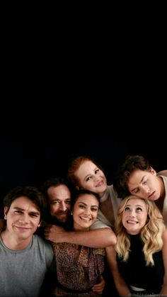 a group of people are posing together for a photo in front of a black background