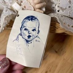 a hand holding up a drawing of a baby