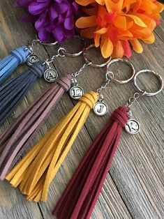 four tasselled key chains with charms on them sitting next to an orange flower