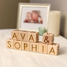 wooden blocks spelling the word ava and sophiia on a table next to a framed photo