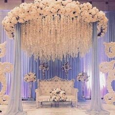 an elegant wedding setup with white flowers and blue drapes on the wall, chandelier