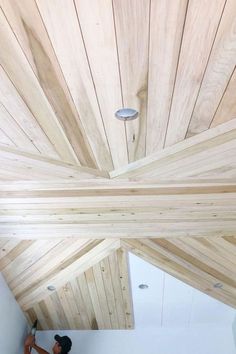 a person is painting the ceiling in a room with wood planks and white walls