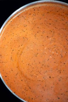 a pan filled with sauce sitting on top of a stove next to a black counter