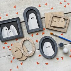 three wooden frames with ghost faces on them and two other items next to it, including a pair of scissors