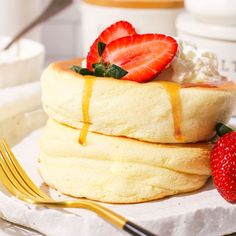 a stack of pancakes with strawberries on top and syrup drizzled over them