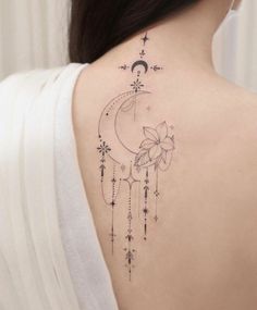 the back of a woman's shoulder with a flower and crescent tattoo on it