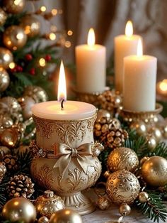 three lit candles sitting on top of a table next to christmas decorations and pine cones