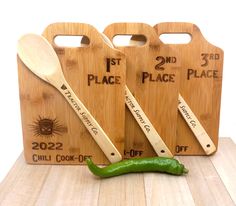 three wooden cutting boards with spoons and two green peppers next to each other on a table