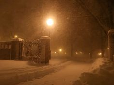 a snow covered street at night with the lights on