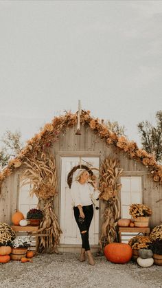 a woman standing in front of a barn with pumpkins