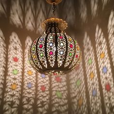 an intricately designed light fixture casts a shadow on the wall with colorful circles and leaves