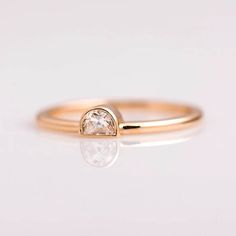 a gold ring with a white diamond in the center and a small round stone on top