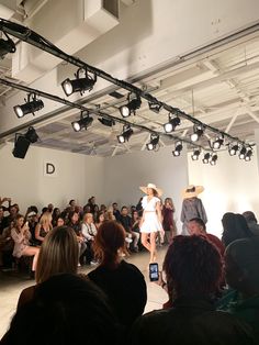 a group of people sitting and standing in front of a crowd at a fashion show