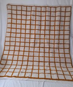 an orange and white checkered blanket on a bed