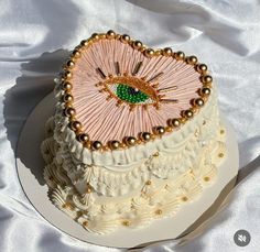 a heart shaped cake decorated with pearls and beaded decorations on a white table cloth