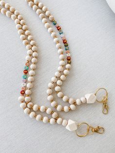 a white beaded necklace with gold clasps on a white tablecloth next to a pair of scissors