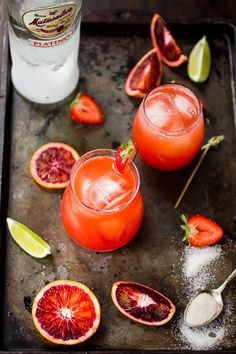 two glasses filled with blood orange margaritas and garnished with lime