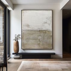 an abstract painting hangs on the wall next to a large vase