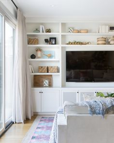 a living room filled with furniture and a flat screen tv mounted on a wall next to a window