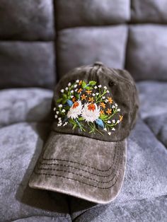 a brown hat with flowers on it sitting on a gray couch next to a pillow