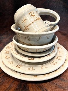 a stack of ceramic dishes sitting on top of a wooden table next to each other