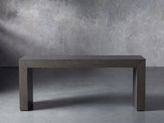 a wooden table sitting on top of a cement floor next to a gray concrete wall