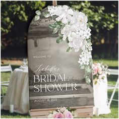 the welcome sign is decorated with flowers and greenery for an outdoor bridal shower