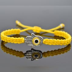 Durable Hand-Made Soft Yellow String Hamsa Hand Bracelet With An Evil Eye For Wrist Sizes 6 Inches To 9 Inches, With An Easy To Use Zip Like Function To Fit Your Wrist. Made From High Quality Soft Yellow String, It Will Be Sure To Last. The Hamsa Hand Is An Ancient Middle Eastern Amulet Symbolizing The Hand Of God. In All Faiths It Is A Protective Sign. It Brings Its Owner Happiness, Luck, Health, And Good Fortune. Each Bracelet Is Carefully Handcrafted And Give Proper Time To Ensure Quality. Yellow Jewelry With Sliding Knot For Festival, Yellow Adjustable Cord Bracelet, Yellow Adjustable Length Jewelry For Beach, Yellow Sliding Knot Bracelet, Yellow Braided Bracelets For Beach, Adjustable Yellow Bracelets As Gift, Adjustable Yellow Bracelets For Gifts, Adjustable Yellow Bracelets, Adjustable Cord Yellow Bracelet For Beach