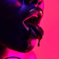 a woman with her mouth open and dripping water on her lips in the pink light