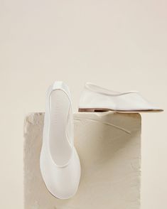 a pair of white shoes sitting on top of a stone block next to a shoe box