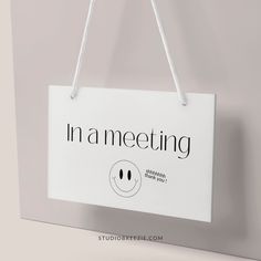 a sign hanging from the side of a wall that says in a meeting with two faces drawn on it