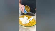 a person pouring corn into a glass bowl