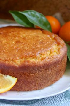 a close up of a cake on a plate with oranges and leaves around it