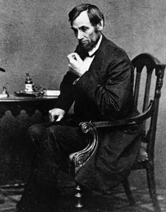 an old black and white photo of a man sitting at a table