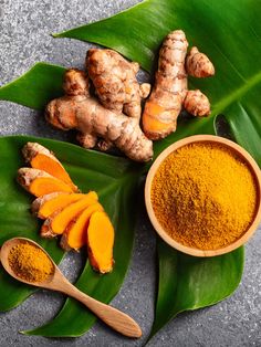 tumerical and ginger powder on top of leaves with spoons next to it